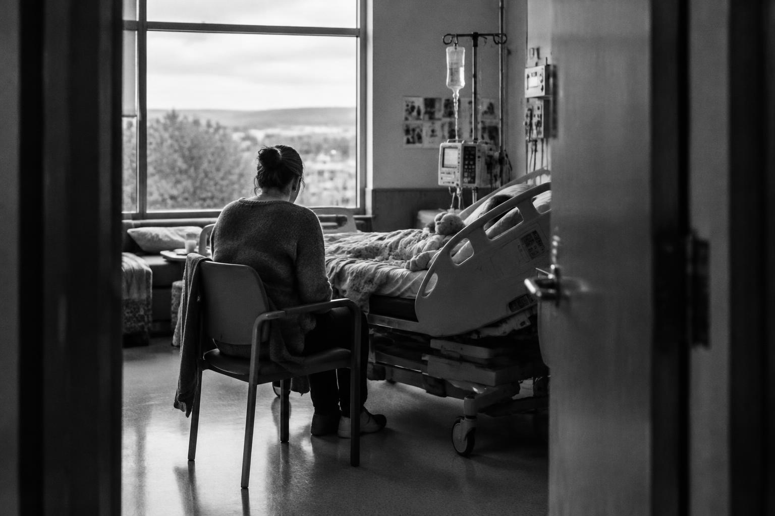 A parent seated beside a child’s hospital bed